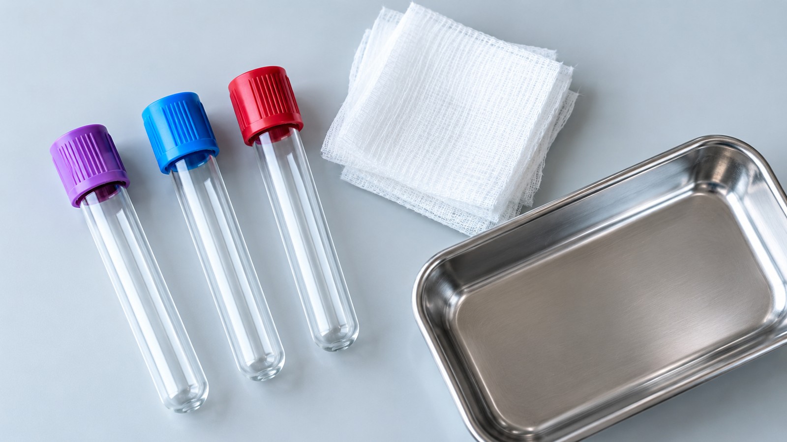 Blood-draw tubes, folded gauze, and a metal tray on a counter.