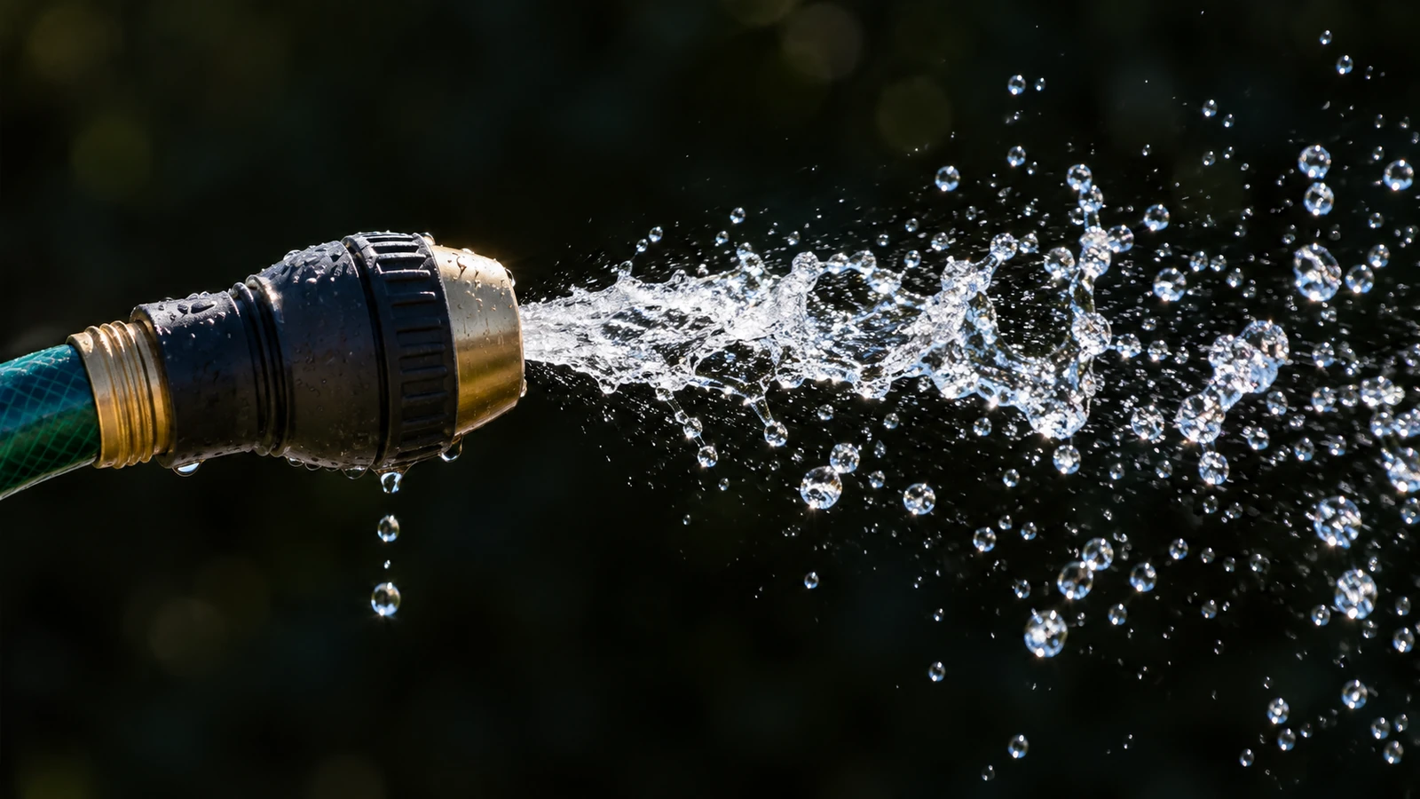 Water pulsing in short bursts from a garden hose nozzle, droplets frozen in the air.